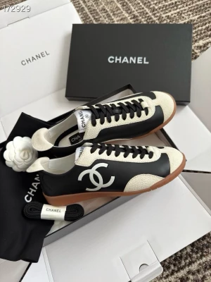 Chanel svarta och vita sneakers - Snygga sneakers från Chanel i svart och vitt med klassisk CC-logga på sidan. Skorna har svarta skosnören, vit plös och detaljer i gräddvitt läder samt brun sula. Perfekt för dig som gillar exklusiv och trendig streetstyle.