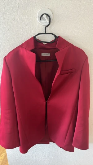 Hunkydory Stockholm röd kavaj/blazer - Säljer min fina röda kavaj från Hunkydory Stockholm i storlek XS. Den är i jättebra skick och använd fåtal gånger! ✨ Fin glansig yta i stark röd färg. Klassiska slag, bröstficka och kortare modell som sitter snyggt. Perfekt till jeans, kjol eller fest. 100% polyester. Mycket bra skick – inga fläckar eller defekter. Frågor? Skriv gärna! Kan skickas snabbt 😊