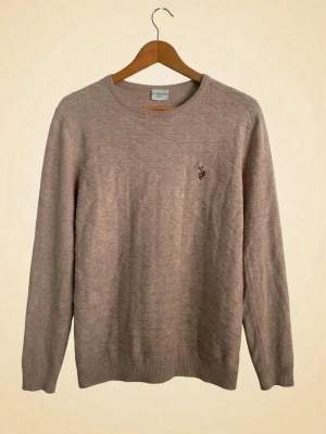 Beige tröja från U.S. Polo Assn - Snygg beige stickad tröja från U.S. Polo Assn. med diskret broderad logga på bröstet. Klassisk rund halsringning och tidlös design som passar perfekt till både jeans och chinos. Mjuk och skön kvalitet – perfekt för höst, vinter och svala vårkvällar.  ✔️ Fint skick ✔️ Neutral färg som passar till allt ✔️ Klassisk och stilren modell ✔️ Perfekt för casual, preppy och smart casual stil  Märke: U.S. Polo Assn. Färg: Beige / Sand Passform: Regular Fit Skick: Mycket bra  Nyckelord: U.S. Polo Assn, stickad 