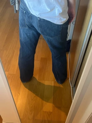Blå raka jeans med låg midja - Säljer ett par klassiska blå jeans med rak passform och låg till medel midja. Jeansen har fem fickor och tydliga sömmar. Perfekta för en avslappnad och stilren look. Materialet är kraftig denim i bomull.