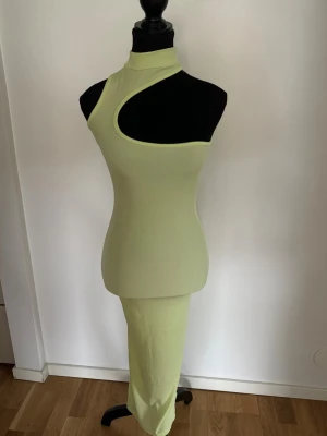 Limegrön cut out maxi klänning - Superfin ribbad maxi klänning i ljus lime/pistagegrön färg med asymmetrisk cut out-design och figurnära passform. Väldigt trendig och minimalistisk modell som passar perfekt till semester, beach club, middag eller sommarfest 