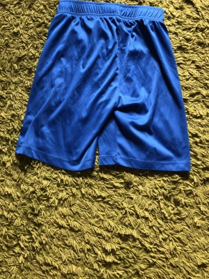 Blå träningsshorts från SOC - Snygga blå träningsshorts från SOC i mjukt och lätt material. Shortsen har resår i midjan för skön passform och är perfekta för sport eller gym. Klassisk design utan extra detaljer.