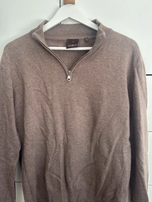 Beige half zip tröja Oscar Jacobson - Säljer en beige/sand tröja från Oscar Jacobson med half zip krage. Tröjan är tillverkad i Kashmir och ull  och har en stilren, klassisk look som passar perfekt till både jeans och chinos. Gjord i Italien och passar bra med skjorta under.