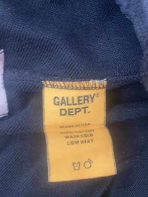  mjukisbyxor från Gallery Dept. - Svarta mjukisbyxor från Gallery Dept. i 100% bomull. Byxorna har raka ben och unika vita detaljer på ena benet. Sköna och stilrena, perfekta för en avslappnad look. Är inte så stor som den ser ut!