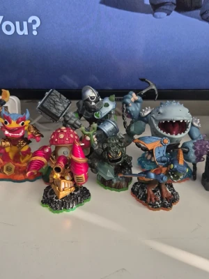 BILLIGT Skylanders-figurer med spelportal - Säljer flera färgglada Skylanders-figurer i plast, perfekta till Skylanders-spelen. Figurerna har olika former och teman, t.ex. drake, robot, svamp och haj. Passar med spelportalen som syns på bilden. Grymma detaljer och cool design!