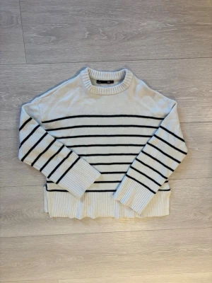 Vit stickad tröja med svarta ränder - Säljer en vit stickad tröja från lager 157.