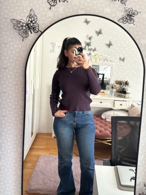 Mörklila ribbstickad tröja - Säljer en mörklila ribbstickad tröja med lång ärm och rund halsringning. Tröjan har en cool cut-out detalj på axeln som ger en trendig touch. Perfekt för dig som gillar en enkel men ändå unik stil.