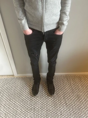 Svarta skinny jeans med slitningar - Säljer ett par svarta/ mörk gråa skinny jeans med slitningar på knäna och lätt tvättad look. Jeansen har klassisk femficksmodell. Perfekta för en trendig och avslappnad stil. Storlek 28 men sitter en aning större skulle säga ungefär w29 modell på jeansen är George! 