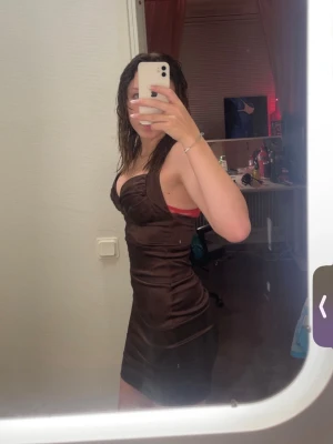 Mörkbrun satin kortklänning - Pris kan diskuteras 🤍En snygg mörkbrun kortklänning i satin med omlott-detalj och öppen rygg. Klänningen är tight och har smala axelband. Dragkedja på ryggen