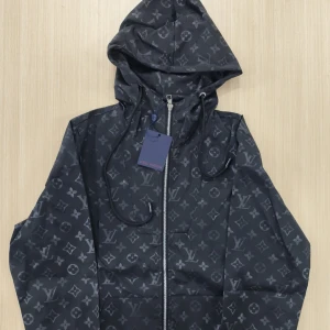 ”Svart Windbreaker Jacka” - ”Svart Windbreaker Jacka” med ikoniskt monogrammönster över hela jackan. Jackan har huva med snörning, hel dragkedja framtill och långärmade ärmar. Precis som ny, använts ett få tal gånger. Pris kan diskuteras vid köp. Prislappen på bilden kommer ej med jackan. Passar även storlek M.