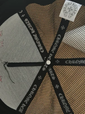 Svart Chrome Hearts keps med röda kors - Säljer en svart keps från Chrome Hearts med tre röda kors i läder framtill. Kepsen har mesh på sidorna och justerbar snapback. Insidan har band med Chrome Hearts-logga och detaljer i vitt. Perfekt för dig som gillar streetwear och vill sticka ut.