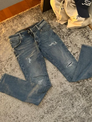 Jack and Jones jeans  - Säljer ett par blå jeans från Jack & Jones med snygga slitningar och distressed detaljer. Klassisk femficksmodell med normal midja och perfekt till sommarn. Nypris 900 kr. Mitt pris: 250