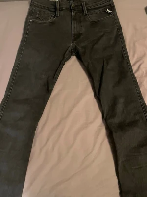 Svarta slim fit jeans från Replay - Snygga svarta slim fit jeans från Replay med klassisk femficksdesign och diskret logga på fickan. Jeansen har normal midja, bälteshällor och är tillverkade i ett stretchigt denimtyg för extra komfort. Perfekta för en trendig och avslappnad stil.