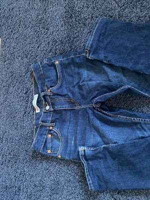 Levi's 512 Slim Taper jeans blå - Säljer ett par klassiska Levi's 512 Slim Taper jeans i mörkblå denim. Modellen har smal passform med avsmalnande ben och snygga kontrastsömmar. Perfekta för dig som gillar en modern och stilren look. Hör av er vid frågor eller funderingar 