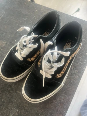 Vans svart leopardmönster - (STORLEK 33) skulle passa en 9-10 åring. Svarta Vans Old Skool sneakers  med vit sula, vita skosnören och en snygg leopardmönstrad sidostrip. Klassisk låg modell i mocka. 