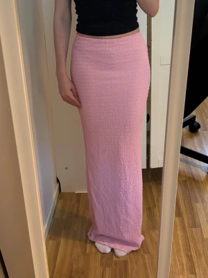 Ljusrosa långkjol i stretchigt tyg - Säljer en ljusrosa långkjol med ett stretchigt, strukturerat material som sitter snyggt mot kroppen. 