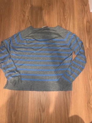 Gråblå randig stickad tröja Zara - Säljer en stickad tröja från Zara i storlek M men skulle säga de är med som S . Tröjan är grå med horisontella blå ränder, har långa ärmar och rund hals. Perfekt för dig som gillar enkel men snygg stil. Materialet känns mjukt och bekvämt.