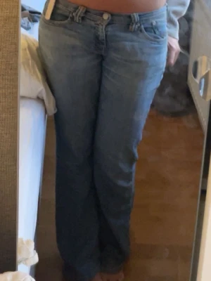 Lågmidjade Levis jeans - Säljer ett par ljusblå jeans med klassisk femficksdesign. Jeansen har låg midja och är tillverkade i denim. Perfekta för en avslappnad och stilren look. Så så snygga! Har ett större hål på bakdelen och en svart fläck. Även slitna längst ner❣️passar mig som har storlek M