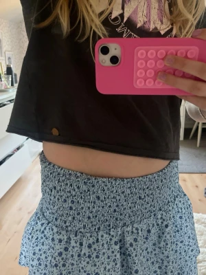 Blommig volangkjol i blått - Söt ljusblå kjol med mörkblå småblommigt mönster och bred smock i midjan. Kjolen har dubbla volanger som ger en luftig och trendig look. Från Gina Young i storlek 158/164❤️