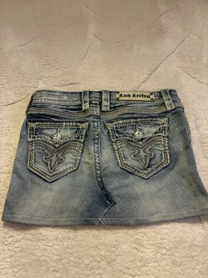 Lågmidjad jeanskjol från Rock Revival - Midjemått rakt över är 37cm. Storlek 26, passar xs/ liten s. Köpt second hand men aldrig använd av mig 💕