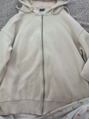 Beige hoodie med dragkedja Gina Tricot - Snygg beige hoodie från Gina Tricot i storlek S. Hoodien har dragkedja framtill, huva med dragsko och ribbade muddar vid ärmslut och nederkant. Perfekt för en avslappnad och trendig look. Fick av en kompis så är använd 