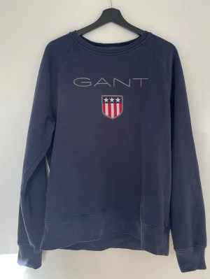 GANT sweatshirt – storlek XL - Snygg och stilren sweatshirt från GANT i mörkblå färg med klassisk logga framtill. Bra skick och perfekt till både vardag och casual outfits.  💰 Prisvärd – hör av dig vid intresse