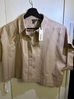 Beige linneskjorta från Buffalo - Kortärmad skjorta i beige från Buffalo David Bitton. Tillverkad i linne för en luftig känsla, med klassisk krage och knappar framtill. 