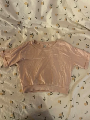 Ljusrosa croppad t-shirt från lager 157 barn st130 - Söt ljusrosa croppad t-shirt från lager 157 med rund halsringning och korta ärmar. Tillverkad i mjuk bomull. Barn storlek 130