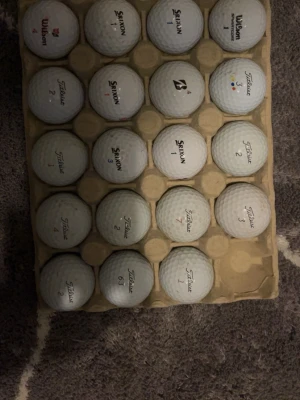Golfbollar B klass - Säljer ett blandat set golfbollar från märkena Titleist, Srixon, Wilson och Bridgestone. Bollarna är vita och ligger i en kartong för enkel förvaring. Perfekt för dig som vill fylla på golfbagen med olika märken.