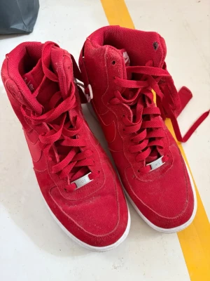 Nike Air Force 1 High Röd - Snygga Nike Air Force 1 High sneakers i helrött med klassisk vit logga på plösen. 
