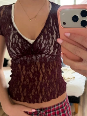 Vinröd spetsig croppad topp - Vinröd, transparent och croppad topp i spets med v-ringning och korta ärmar. Snyggt mönster i spetsen och figurnära passform. Perfekt att styla lager på lager.