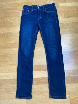Levi's 512 Slim Taper – Mörkblå - Säljer ett par klassiska mörkblå jeans från Levi's med raka ben och femficksmodell. Jeansen har orange sömmar och en liten röd Levi's-tag på bakfickan. Perfekta till en avslappnad stil och tillverkade i bomullsdenim.
