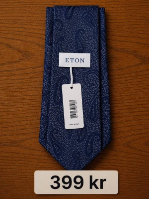 Mörkblå paisleyslips från Eton - Snygg mörkblå slips från Eton med paisleymönster. Perfekt accessoar för att lyfta din outfit med en klassisk och stilren touch. Slipsen är tillverkad i ett exklusivt material och har en elegant struktur. Paketpris 1600kr. Bra pris per styck – nypris ca 1000–1500 kr