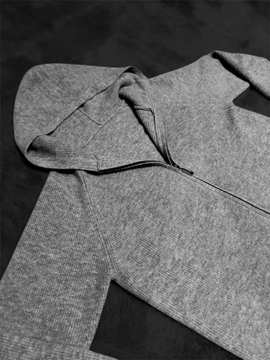 Grå zip-hoodie med huva - En stilren grå hoodie med dragkedja och huva. Tröjan är ribbstickad och har långa ärmar samt muddar vid ärmslut och nederkant. Perfekt för en avslappnad look och enkel att matcha med jeans eller joggers.