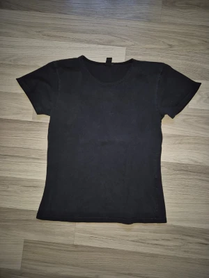 Svart basic t-shirt med rund hals - Enkel svart t-shirt med rund halsringning och korta ärmar. Modellen är figurnära och passar perfekt till jeans eller shorts. T-shirten är tillverkad i mjukt bomullstyg för en bekväm känsla hela dagen.