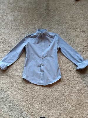 Ralph lauren skjorta - Riktigt fräsch Ralph lauren skjorta till sommaren i en snygg ljusblå färg som passar perfekt med sommar färgerna. Hör av er vid frågor eller funderingar!