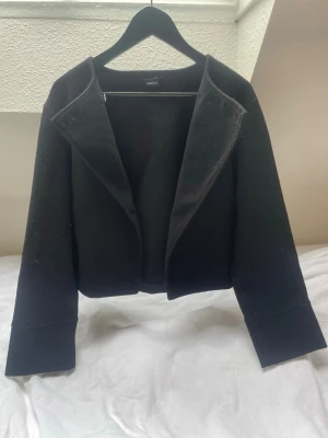 Svart kappa från Gina tricot - svart kappa med öppen front och breda slag. Kortare modell med raka ärmar💕