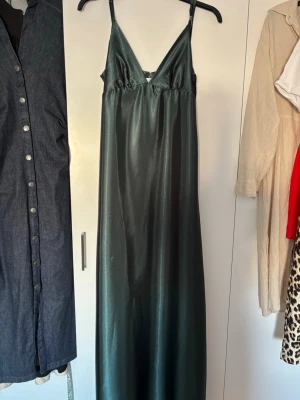 Mörkgrön långklänning i satin - Elegant mörkgrön långklänning med smala axelband och v-ringning. perfekt balklänning 