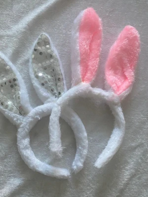 Fluffiga hårband med kaninöron - Två hårband med kaninöron i mjukt vitt material. Ena paret har rosa insida på öronen, andra har silverfärgade paljetter. Perfekt för att skapa en lekfull look eller till maskerad. Materialet är syntetiskt och fluffigt. Helt ny 