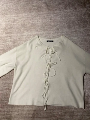 Beige topp med snörning från Gina Tricot - Trendig beige topp från Gina Tricot med långa ärmar och snygg snörning framtill. Perfekt att styla med jeans eller kjol.