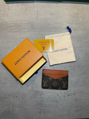 monogram kortfodral - Snyggt kortfodral  i klassiskt brunt monogrammönster med detaljer i cognacsfärgat läder. Slimmad design med flera kortfack, perfekt för dig som vill ha stil och funktion i ett. Kommer med original ask och dustbag.