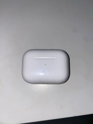 Apple AirPods Pro 2 laddningsetui - Säljer ett vitt laddningsetui till Apple AirPods Pro 2. Etuiet är tillverkat i blank plast och har en smidig, rundad form med magnetiskt lock. Perfekt för att ladda och förvara dina trådlösa hörlurar när du är på språng.