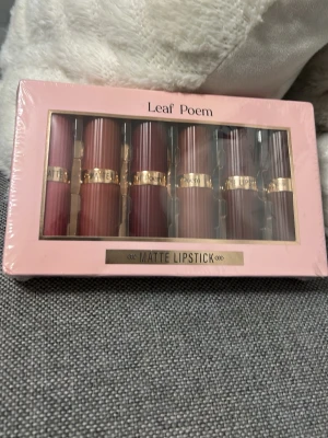 Leaf Poem Matte Lipstick set - Snyggt set med sex matta läppstift från Leaf Poem i olika nyanser av rött, nude och rosa. Hylsorna är randiga med gulddetaljer och varje läppstift har en elegant, stilren design. Perfekt för dig som gillar att variera din look med klassiska färger.