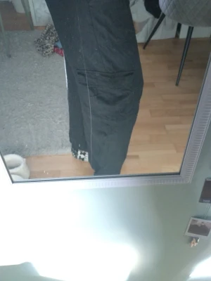 Svarta vida linnebyxor me cargo fickor - Säljer ett par svarta linnebyxor med avslappnad passform och raka ben. Byxorna har fickor på sidorna och är tillverkade i ett lätt och luftigt linnematerial, perfekta för en chill och stilren look. Säljer då det är för korta!