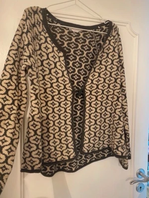 Mönstrad kofta från Rabalder - Snygg stickad kofta från Rabalder i grön och beige med grafiskt mönster. Koftan har långa ärmar, öppen framtill med en knapp 