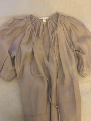 Beige blus med knytband från H&M - Luftig beige blus från H&M med v-ringning och knytband framtill. Super najs på sommaren och sitter bra inte för lång eller för kort, jag är 165.🩷🩷