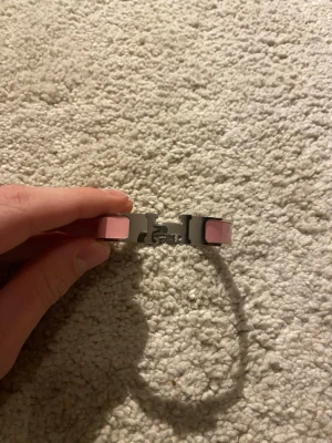 Rosa Clic H armband - Snyggt armband  i silverfärgad metall med rosa emaljdetaljer och det ikoniska H-spännet framtill. Stilren och modern design som passar perfekt till din accessoar-samling.