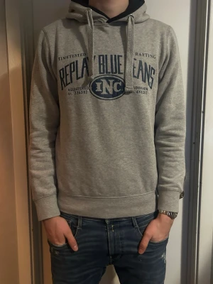 Grå hoodie Replay Blue Jeans - Snygg grå hoodie från Replay Blue Jeans med tryck i mörkblått framtill. Klassisk huva. Strlk M. Skick 8/10. Pris kan diskuteras.