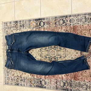 Blå slim jeans från Tiger of Sweden - Säljer ett par blå jeans från Tiger of sweden i slim passform med klassisk femficksdesign och dragkedja. Jeansen har en mörkare tvätt och subtila slitningar. Finns inga defekter, kom gärna med prisförslag!