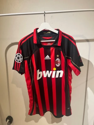 AC Milan matchtröja Kaka #22 Adidas - Säljer en klassisk AC Milan matchtröja från Adidas med Kaka och nummer 22 på ryggen. Tröjan är röd och svart med gulddetaljer, Champions League-märke på ärmen och klubbmärke på bröstet. Shortsen ingår